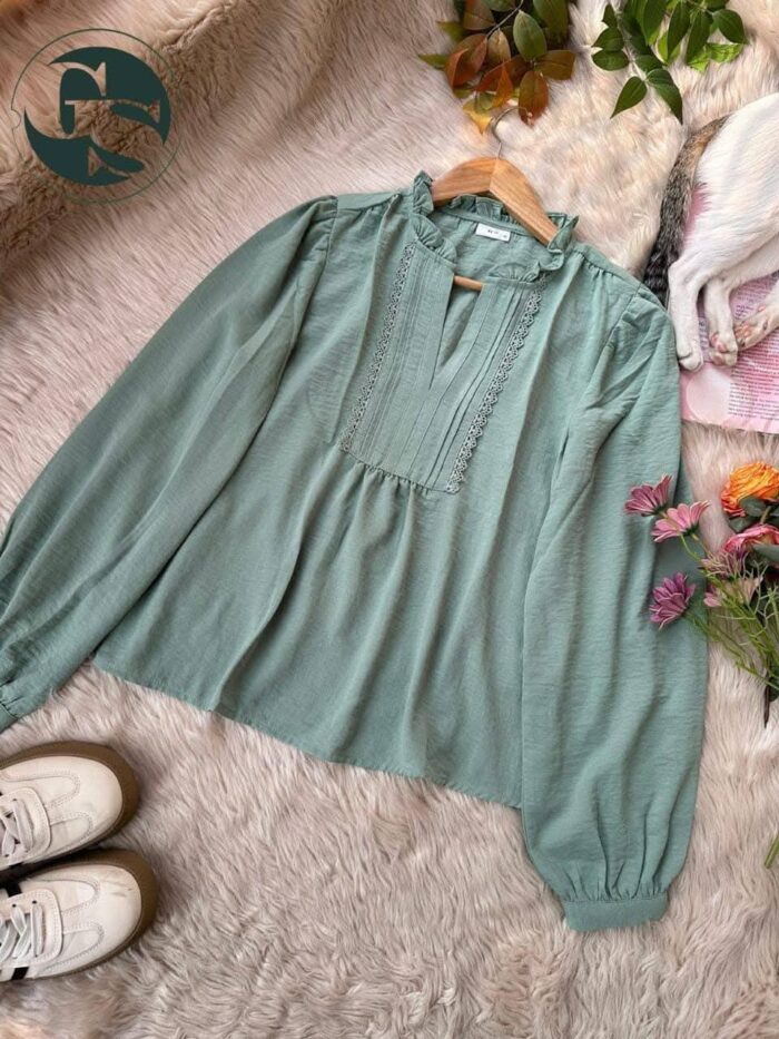 Paste green long sleeve blouse with ruffle neck and lace details laid flat