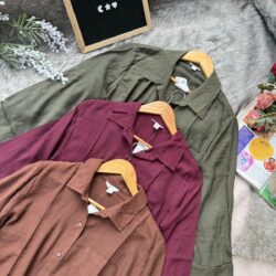 Women's cotton blend button-down shirts in green, burgundy, and brown, displayed on hangers with a casual and stylish look